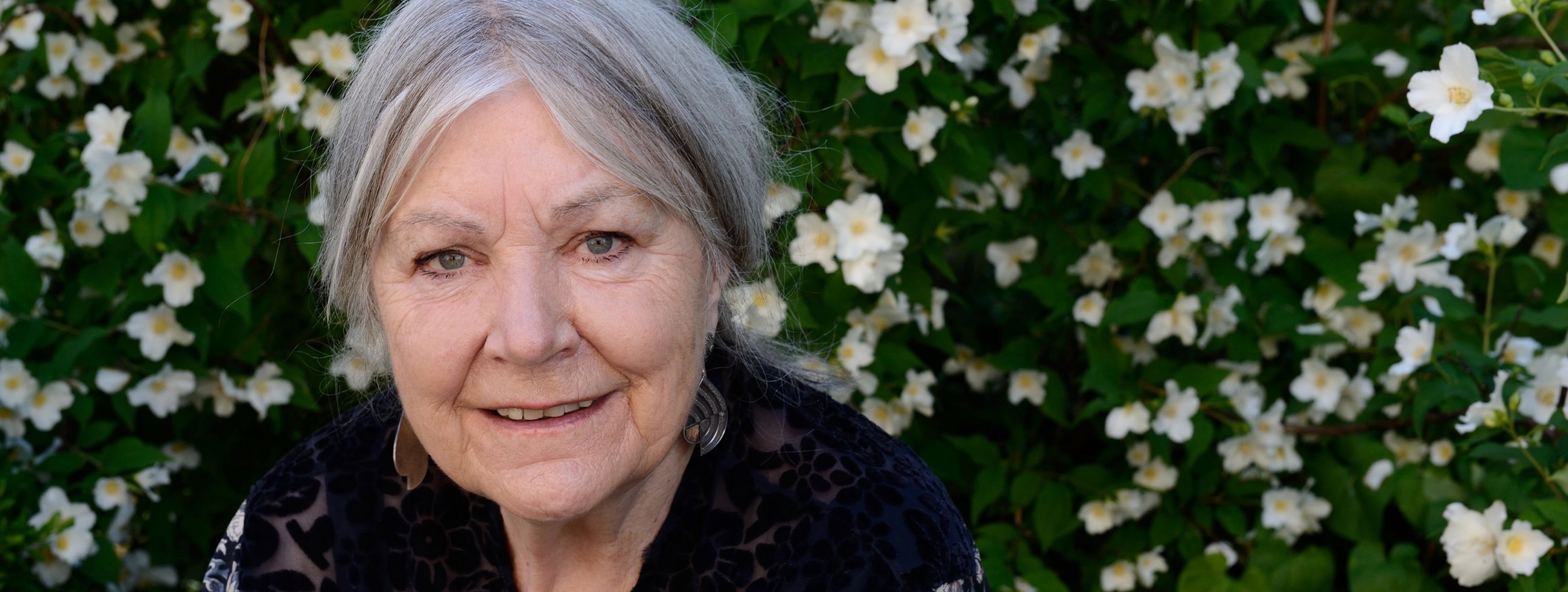 Die Schriftstellerin und Psychologin Helga Schubert vor einer Blumenhecke
