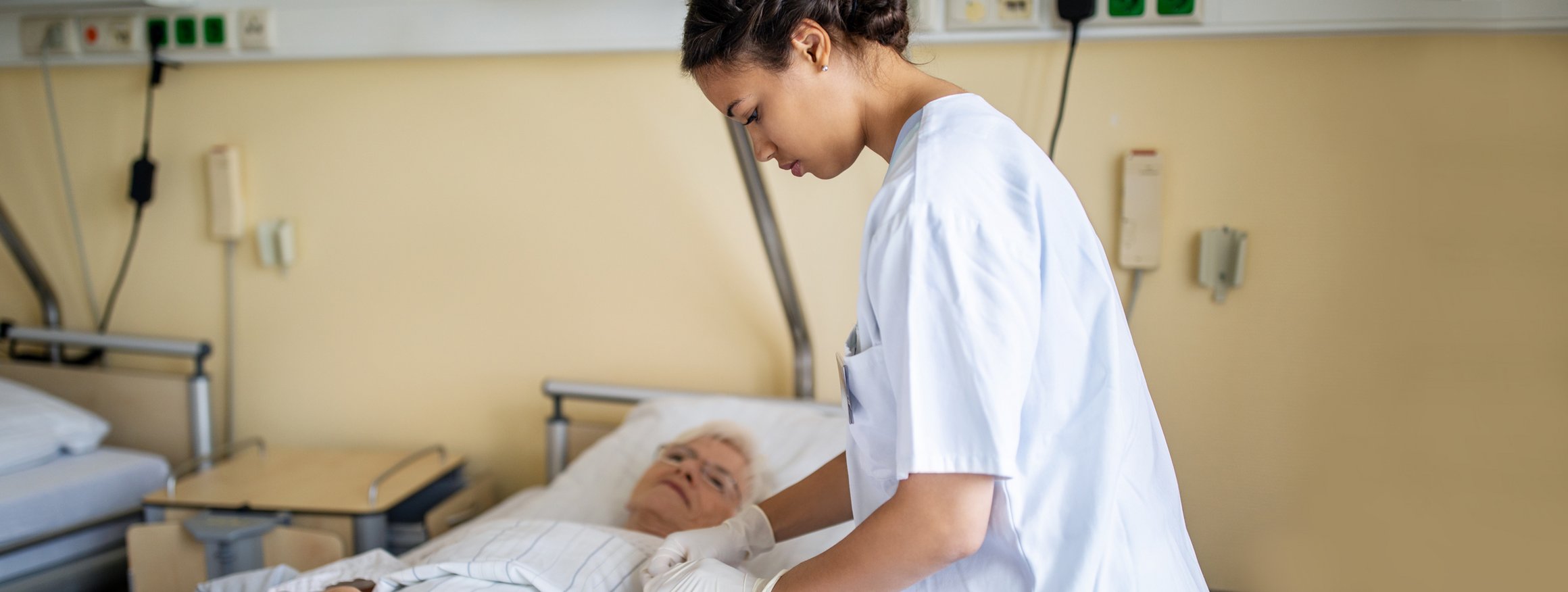 Eine Krankenschwester im Krankenhaus behandelt eine ältere Frau im Krankenbett