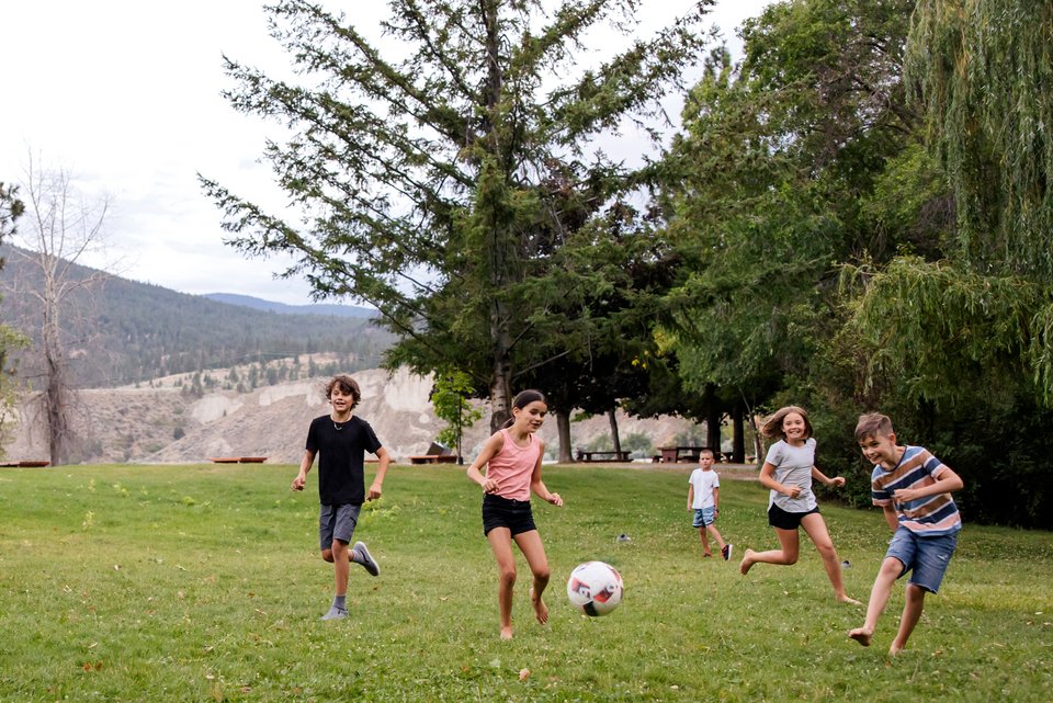 Kinder spielen auf einer Wiese Fußball