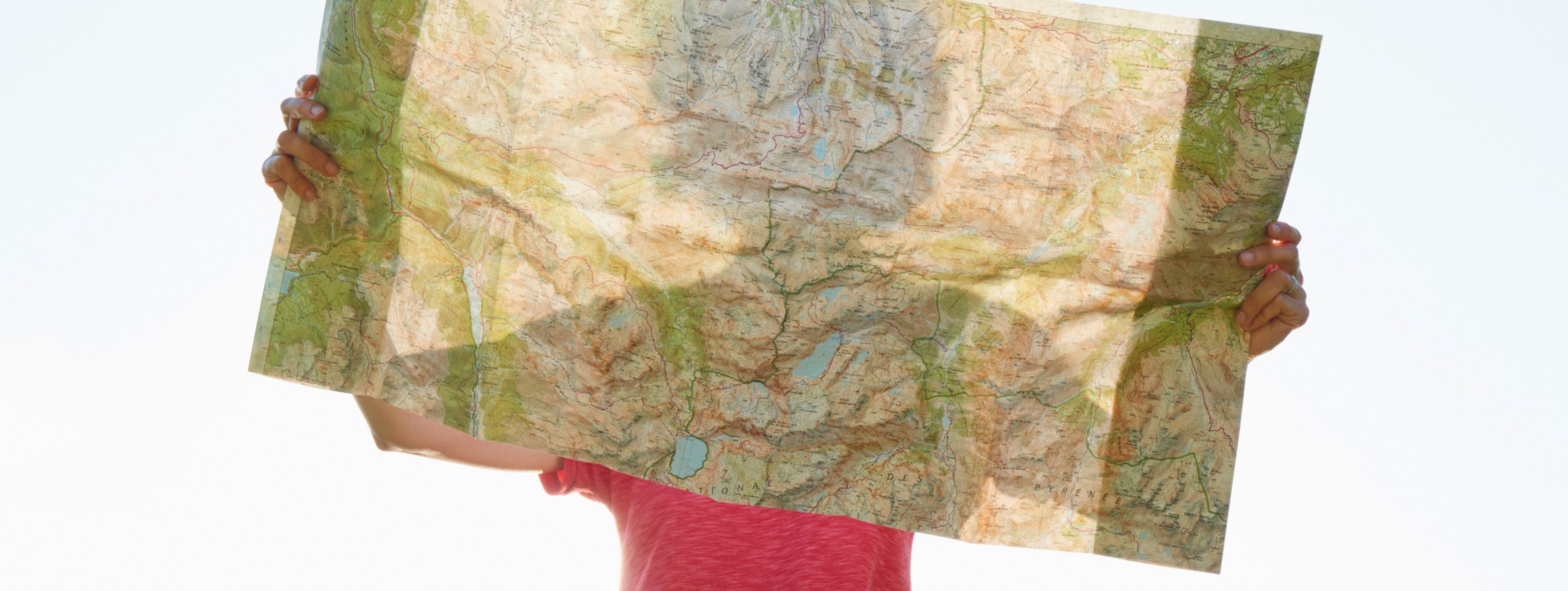 Eine Frau hält eine Landkarte in den Händen vor ihr Gesicht