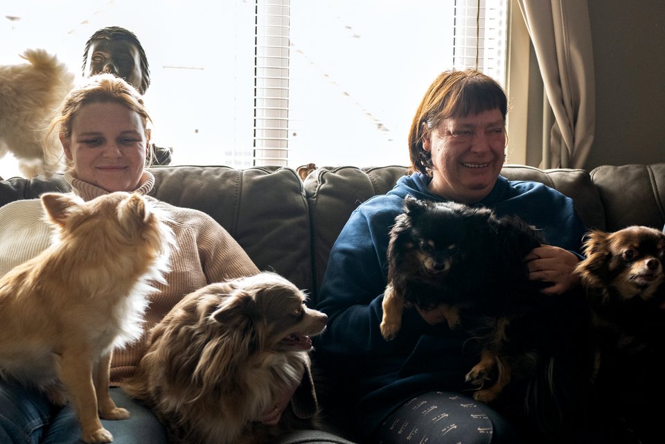 Frauen mit psychischen Erkrankungen sitzen gemeinsam mit ihren Haustieren auf einem Sofa in ihrer WG und lächeln zufrieden