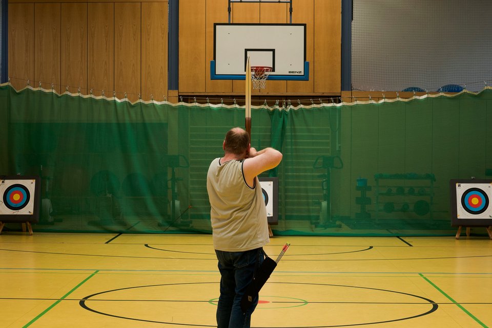 Patientinnen und Patienten in einer Sporthalle beim therapeutischen Bogenschießen