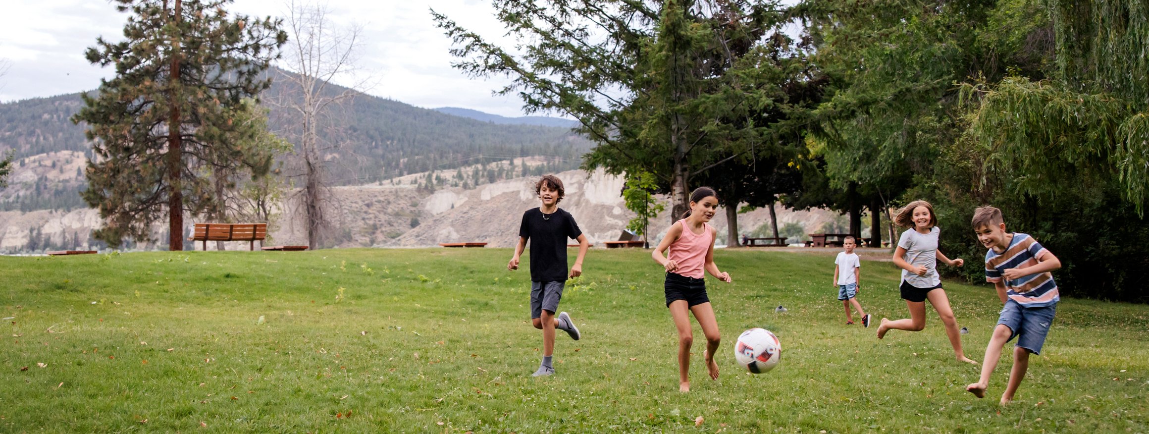 Kinder spielen auf einer Wiese Fußball