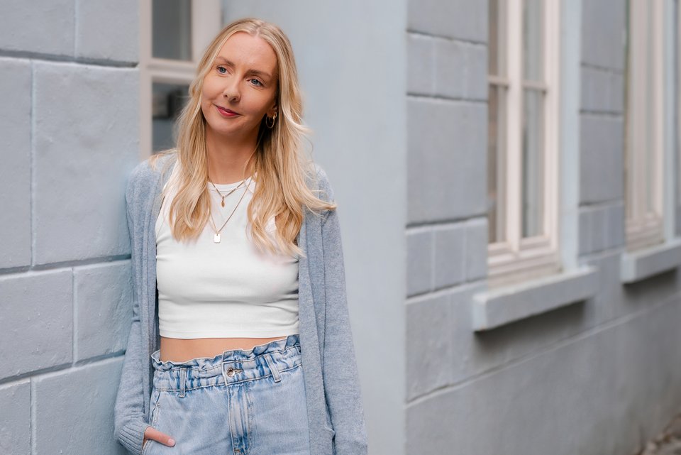 Janina Eilts, die inzwischen Expertin für Essstörungen ist, lehnt entspannt an einer Hauswand, eine Hand in der Jeans